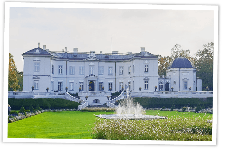 Die Fassade des Bernsteinmuseums in Palanga, Litauen, umgeben von einer gepflegten Gartenanlage mit Springbrunnen.