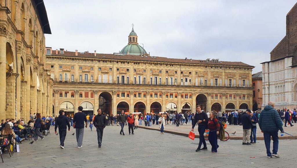 Die belebte Piazza Maggiore in Bologna mit Blick auf die historischen Palazzi und die Kuppel von Santa Maria della Vita.
