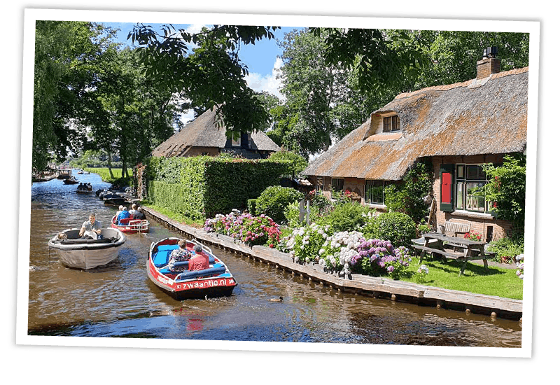 Touristen in kleinen Elektrobooten auf einem Kanal im idyllischen Giethoorn, Niederlande.