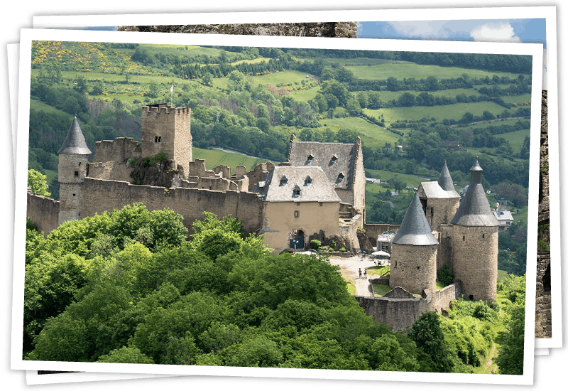 Die historische Burg Burscheid inmitten einer grünen Hügellandschaft in Luxemburg.