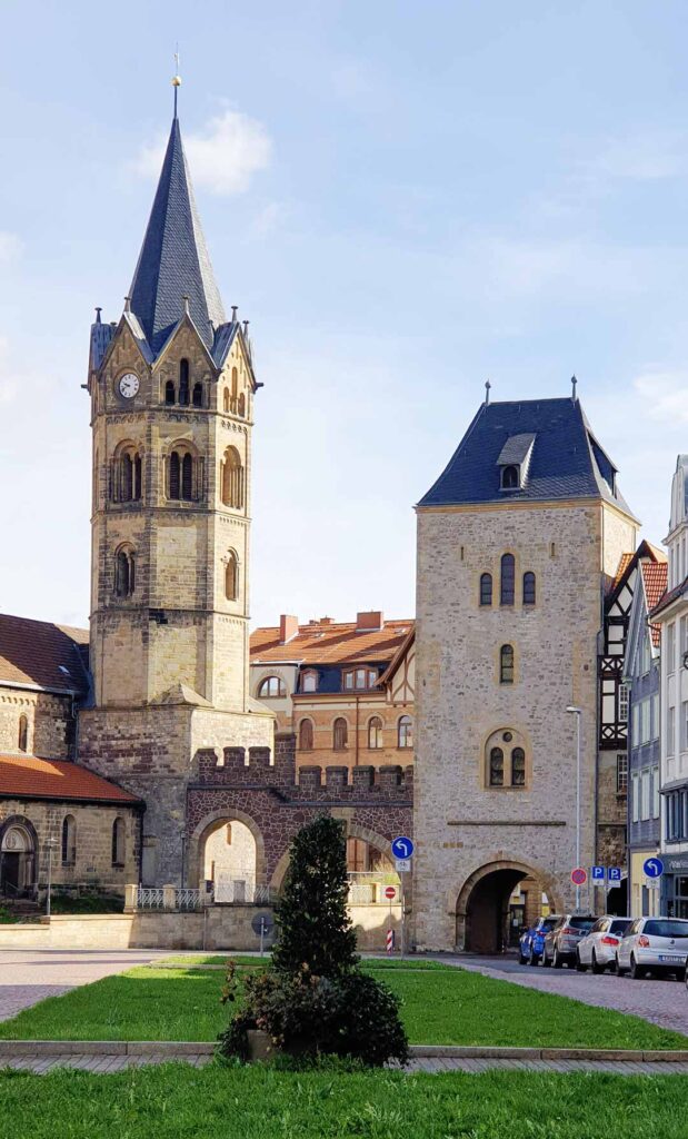 Der hohe Turm der Nikolaikirche neben dem historischen Nikolaitor am Karlsplatz in Eisenach bei sonnigem Wetter.