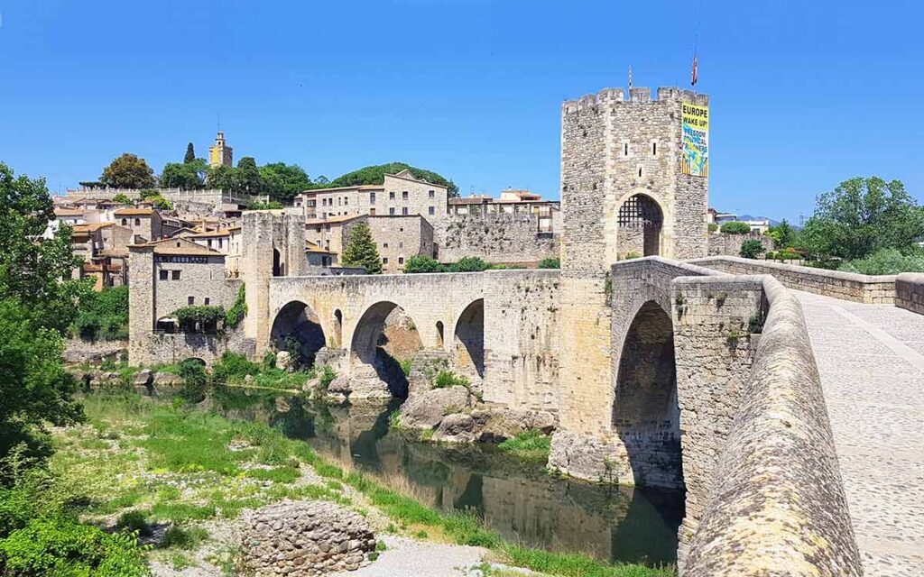 Historische mittelalterliche Steinbrücke mit befestigtem Wehrturm und Stadttor in Besalú nahe Girona (Spanien), die über einen Fluss führt.