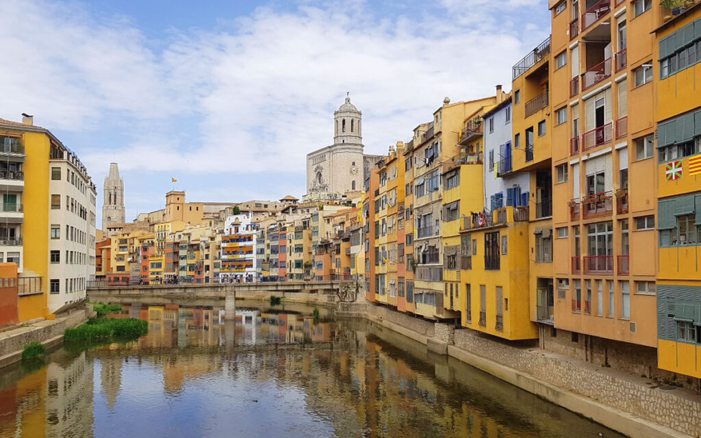 Blick auf die berühmten bunten Häuser (Cases de l'Onyar) am Fluss in Girona mit der Kathedrale im Hintergrund während eines Städtetrips in Spanien.