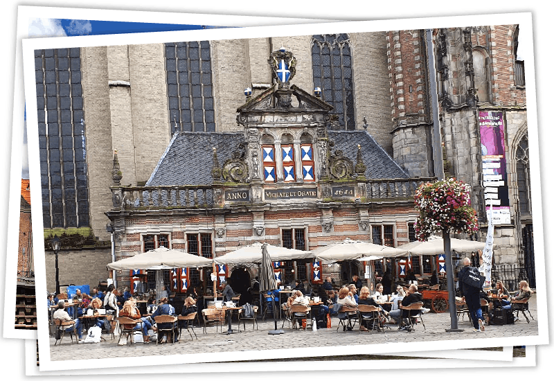 Besucher in einem Straßencafé vor einem historischen Gebäude in der niederländischen Stadt Zwolle.