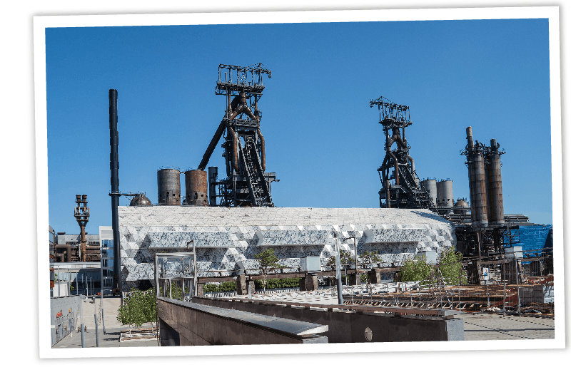 Historische Hochöfen in Esch-Belval, Luxemburg, kombiniert mit moderner Architektur in einem Industriegelände.