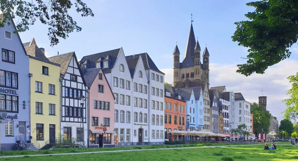 Die bunten historischen Giebelhäuser in der Kölner Altstadt an der Rheinpromenade mit der Kirche Groß St. Martin.