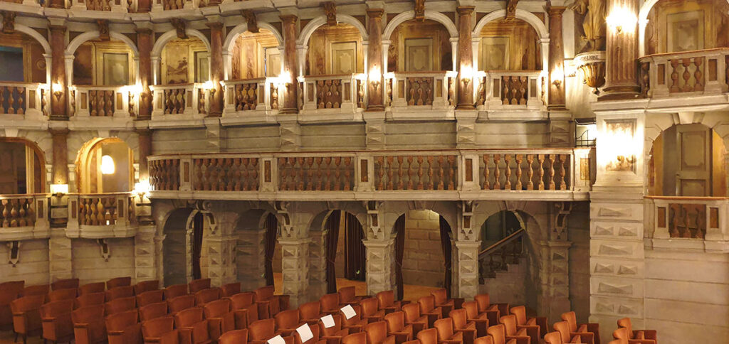 Der prunkvolle Innenraum des Teatro Bibiena in Mantua mit mehrstöckigen Holzlogen, warmem Licht und Blick auf die Zuschauerreihen