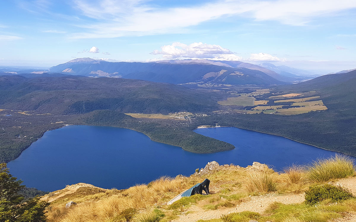Der Mount Robert-Wanderweg führt am Kamm entlang mit freier Sicht auf den Lake Rotoiti und die weite, sonnenbeschienene Landschaft.