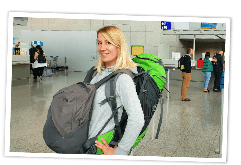 Reisebloggerin mit zwei Rucksäcken im Flughafen