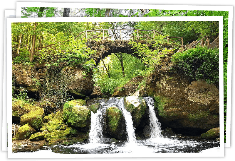 Der malerische Schiessentümpel-Wasserfall mit seiner ikonischen Steinbrücke im Mullerthal, Luxemburg.