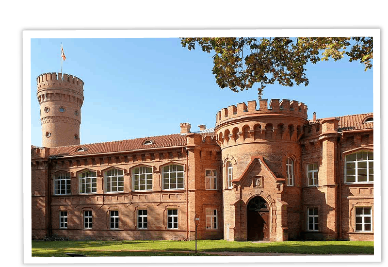 Die historische Fassade von Schloss Raudone in Litauen mit ihrem markanten runden Turm und den roten Backsteinmauern.