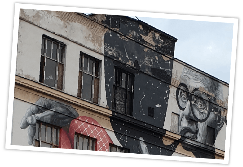 Ein großflächiges Wandgemälde mit einer Porträtzeichnung an einer Hausfassade in Kaunas, Litauen.