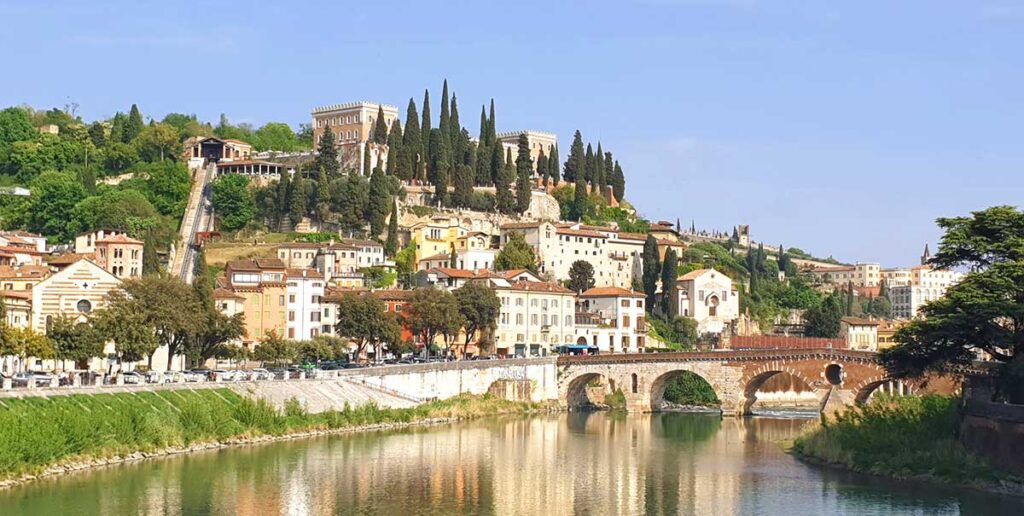 Blick vom Ufer der Etsch auf das Castel San Pietro und die historische Altstadt von Verona.